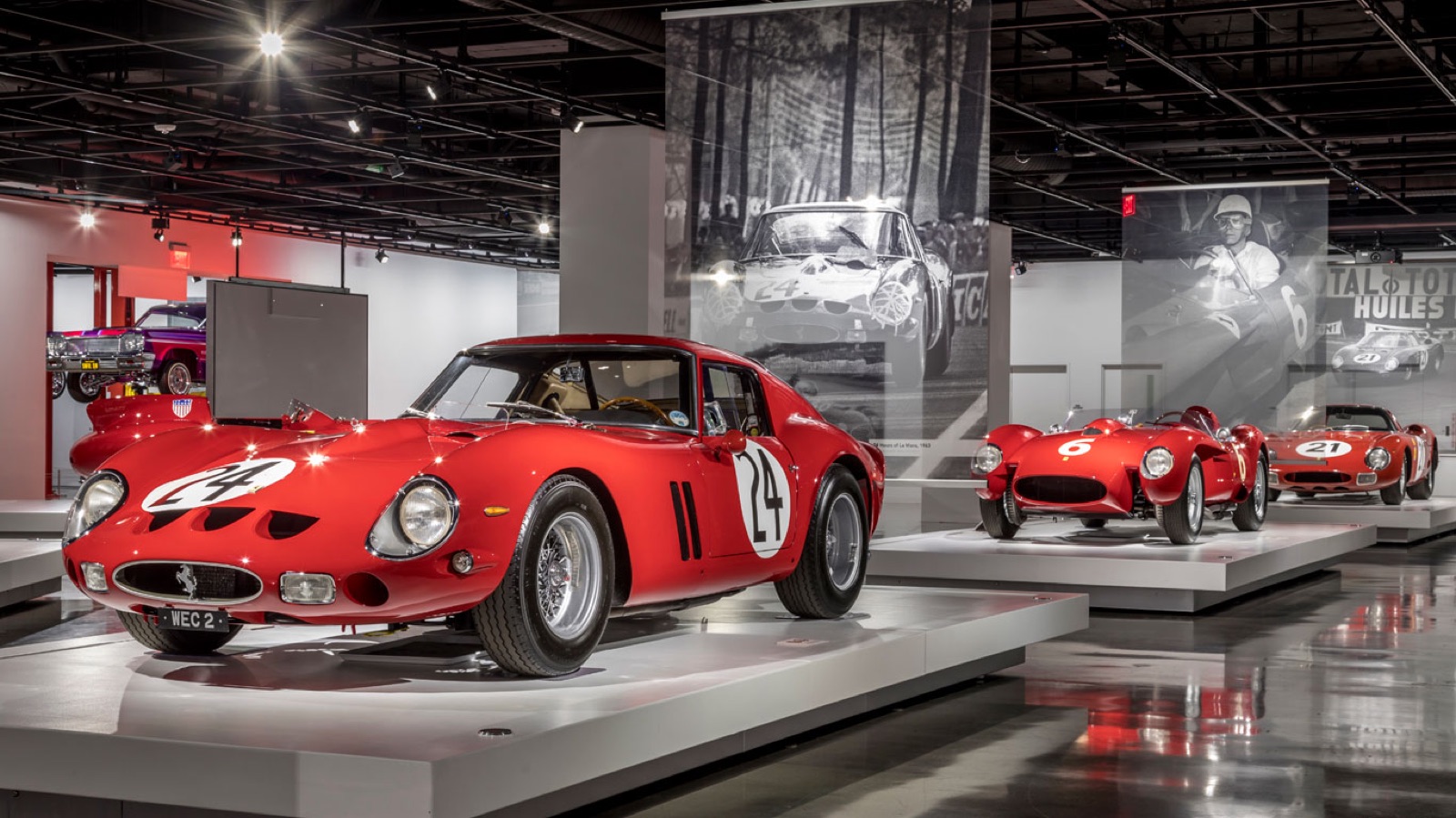 Ferrari 250 GTOs displayed on plinths in a museum