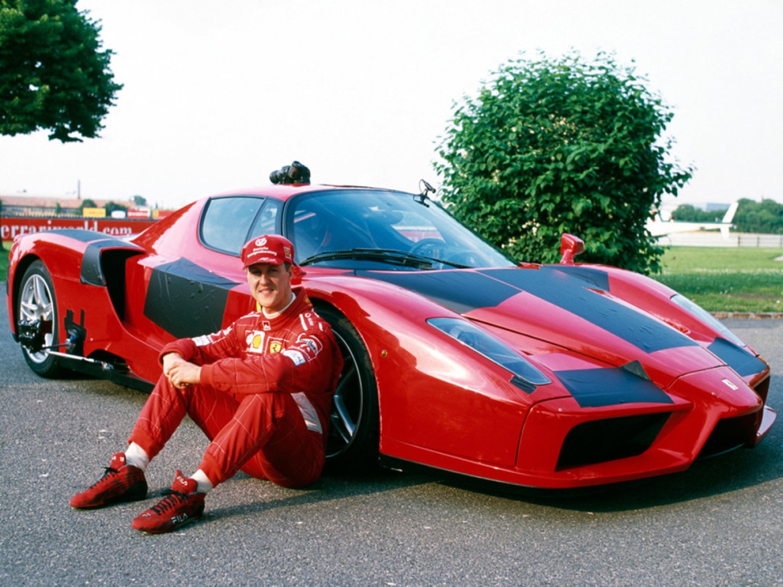 Michael Schumacher sitting in front of a red Ferrari Enzo development prototype